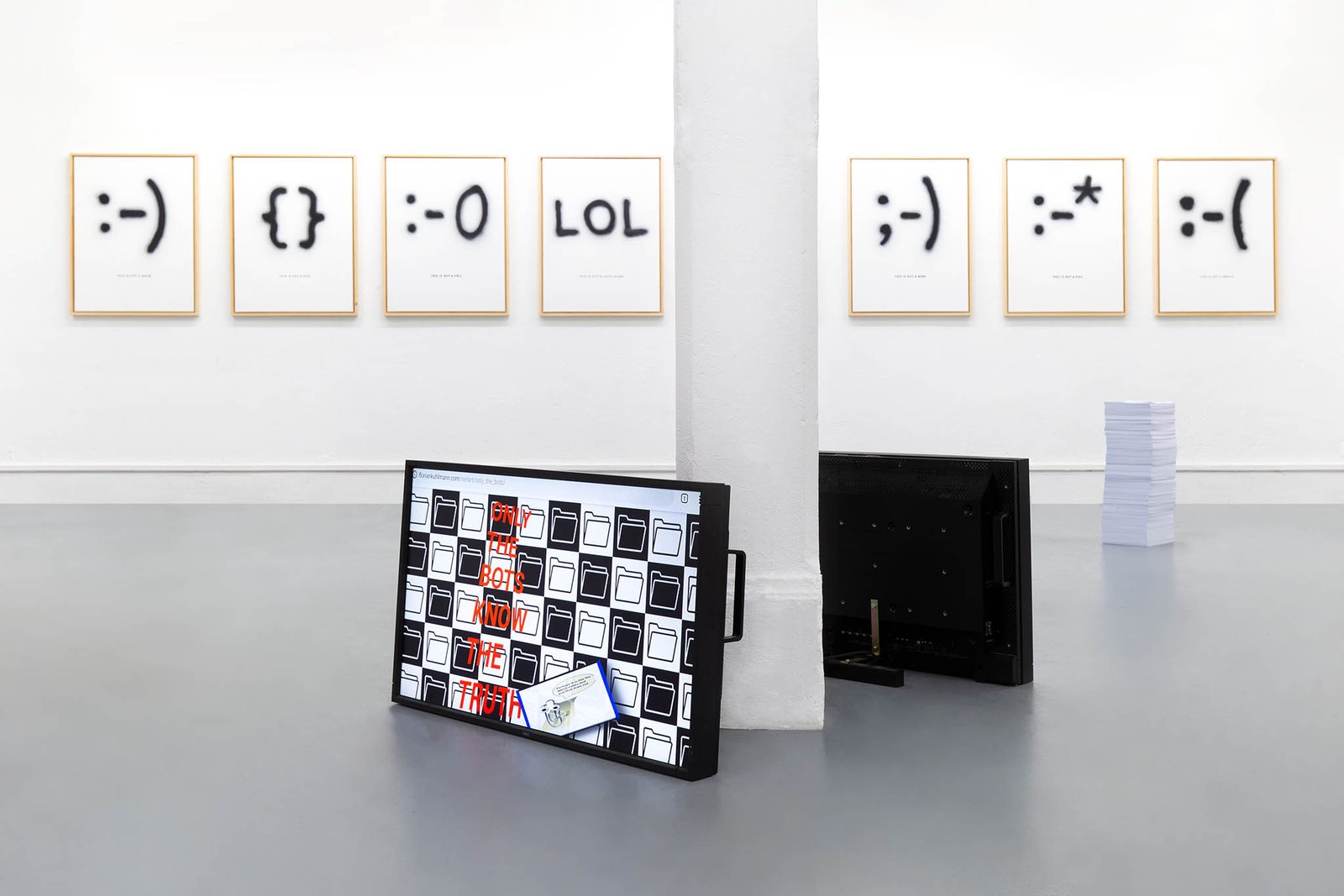 Room with framed emoticons and screens on the floor