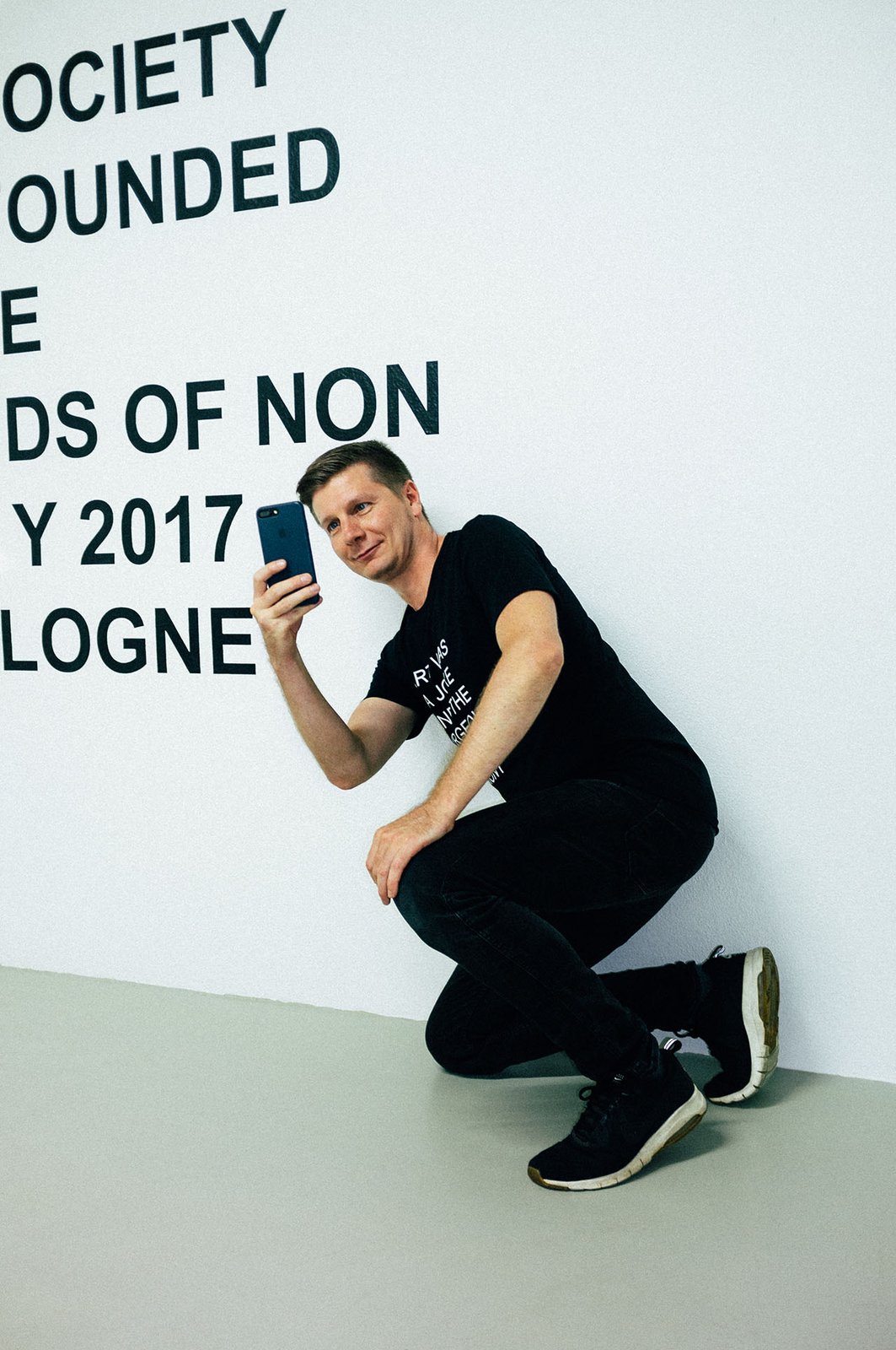 Performer in front of the wall text THE INTERNATIONAL NON SOCIETY